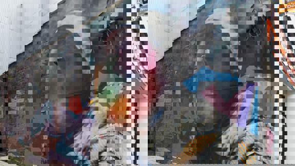 Colourful mural of an astronaut's helmet with a vibrant, abstract background on a brick wall.