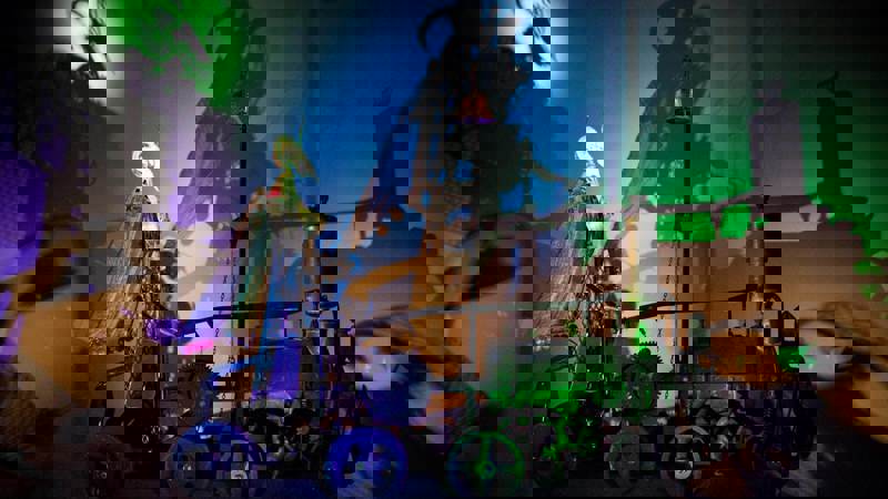 Intricate mechanical sculptures illuminated by colorful lights, casting dramatic shadows on the wall, creating a captivating scene at Sharmanka Kinetic Theatre.