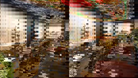 A lavish, Italian-inspired cocktail bar with gold-framed art, candlelit tables, velvet seating, and a dramatic interior styled like a Roman palace.