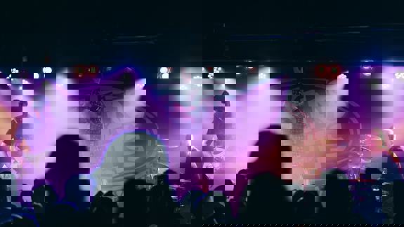 Band performing live at King Tut’s Wah Wah Hut, with dramatic purple lighting and an engaged crowd.