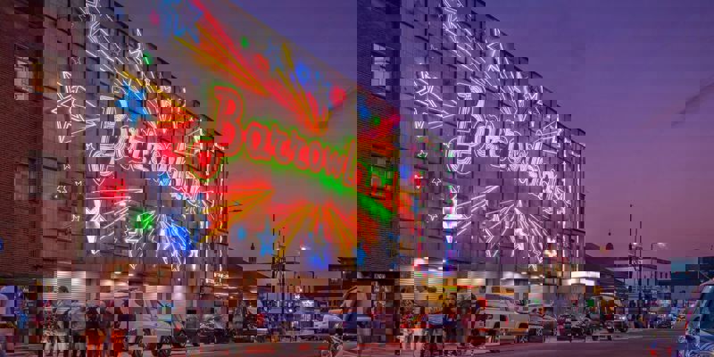 Exterior of the Barrowland Ballroom at dusk with its famous neon sign glowing and people queuing outside.
