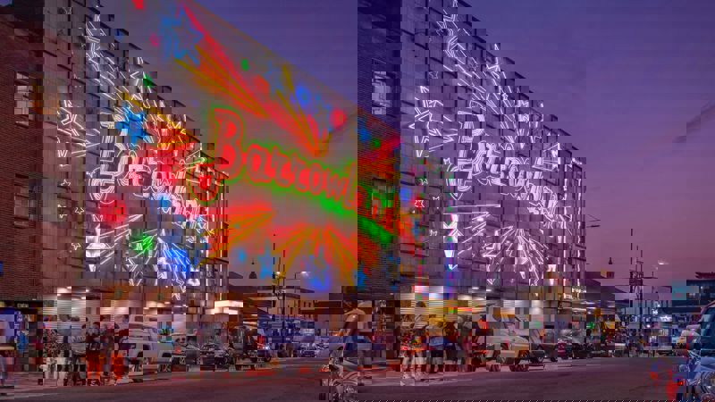 Exterior of the Barrowland Ballroom at dusk with its famous neon sign glowing and people queuing outside.