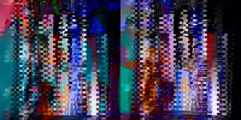 A close-up of a wooden puppet figure in an ornate, dark wooden structure with bells and strings.