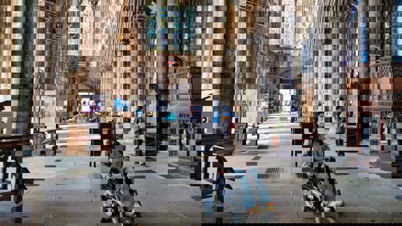 A person in a wheelchair inside the main hall of the Kelvingrove Art Gallery and Museum, with sculptures and a grand staircase in view.