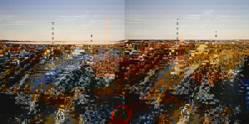 Aerial view of a large outdoor concert at Glasgow Green with crowds gathered and fairground rides nearby.