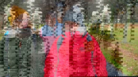 A group of adults of various ages walking down a path in a park during a community health walk.