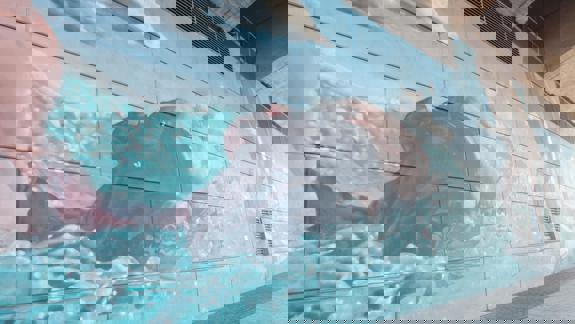 Mural showing a person swimming in a blue, wavy pool, with water splashing around them.