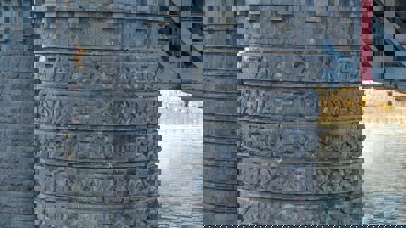 A stone bridge column with inscriptions in both Greek and English, reading "ALL GREAT THINGS STANDS FIRM IN THE STORM."