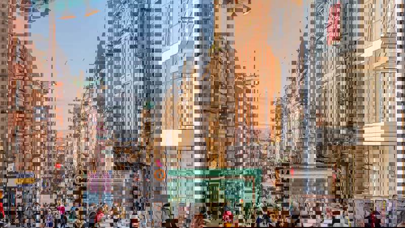 Bustling Buchanan Street in Glasgow with shops and pedestrians under a sunny sky.