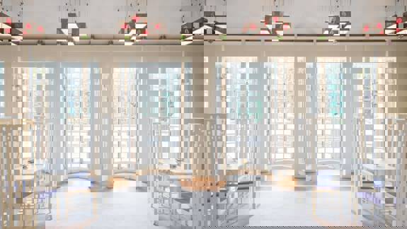 The bright, elegant interior of House for an Art Lover, featuring white, high-backed chairs, square tables, and French windows.