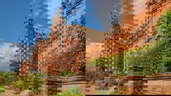 An exterior view of the Kelvingrove Art Gallery and Museum's red-brick building under a blue sky.