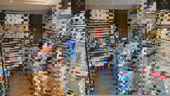 The interior of a small art shop with walls and shelves filled with greeting cards, art prints, and books.