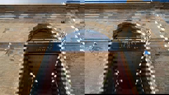 A low-angle shot of the entrance to the Tramway arts venue, featuring a large arched doorway and the building's stone facade.