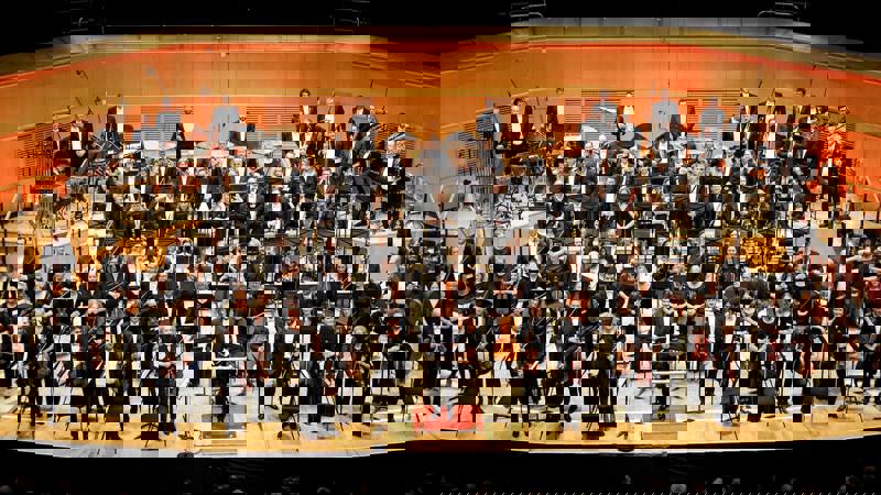 The Royal Scottish National Orchestra on stage at the Glasgow Royal Concert Hall, standing to receive applause. 