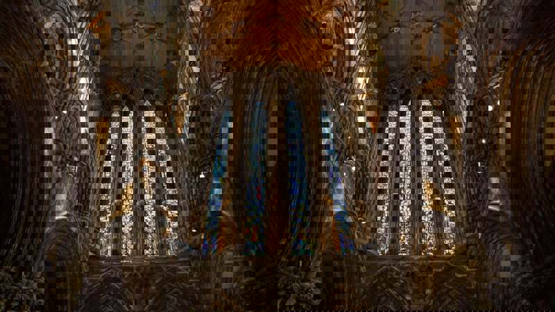 Interior of Glasgow Cathedral with tall stained glass windows and vaulted stone arches.