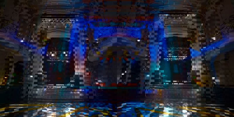 The ornate, empty interior of the O2 Academy Glasgow music venue, featuring a stage lit with blue and yellow spotlights.