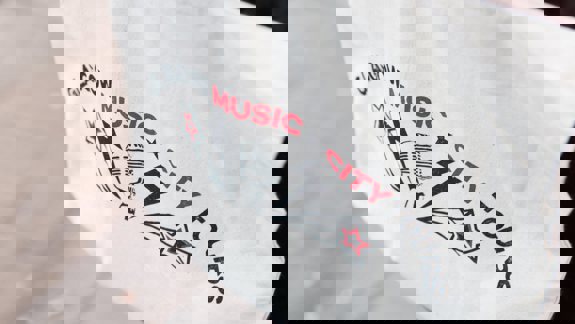 A white canvas bag featuring the "Glasgow Music City Tours" logo in red and black, with stars and a microphone graphic.