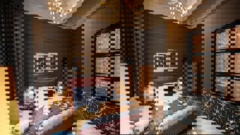 Boutique 50 hotel room in Glasgow featuring a plush velvet bed, freestanding bathtub, rich dark walls, and warm lighting with modern artwork and furniture.