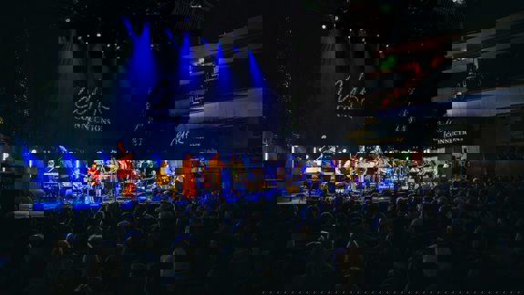 A band performs on a stage lit with spotlights to an audience at the Celtic Connections music festival.