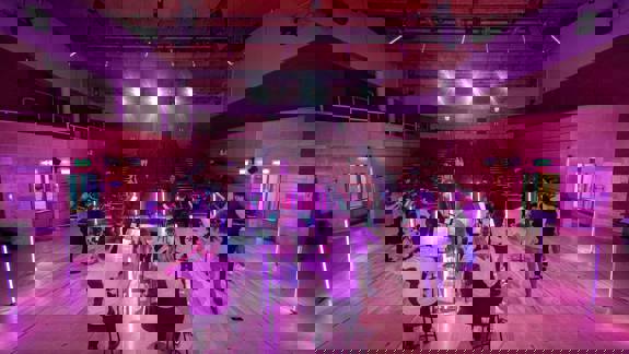 The Scottish Ensemble performs on a stage, with musicians playing string instruments under pink and purple lights.