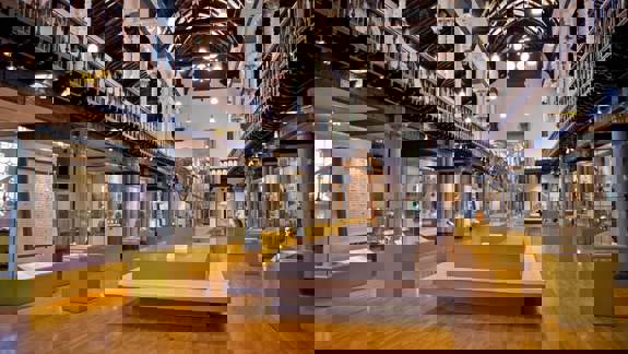 The interior of the Hunterian Museum, showing a large hall with exhibits in glass cases and a high ceiling with intricate ironwork.