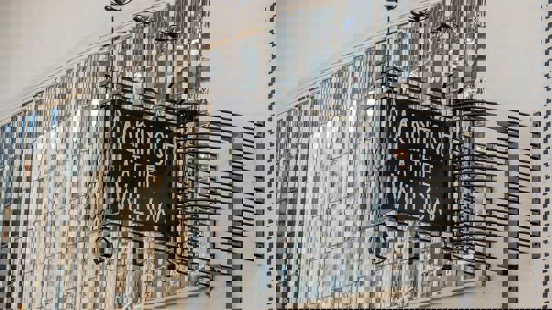 Exterior sign for "MACKINTOSH AT THE WILLOW" against a building with stained glass windows.