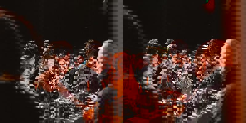 A woman with red hair and a man taste whisky samples at a well-stocked bar counter at a festival.