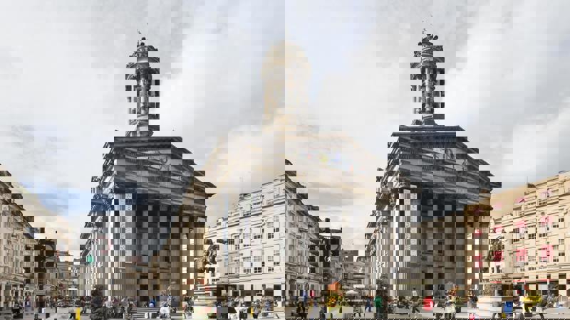 The classical facade of a museum with a statue of a man on a horse in front.