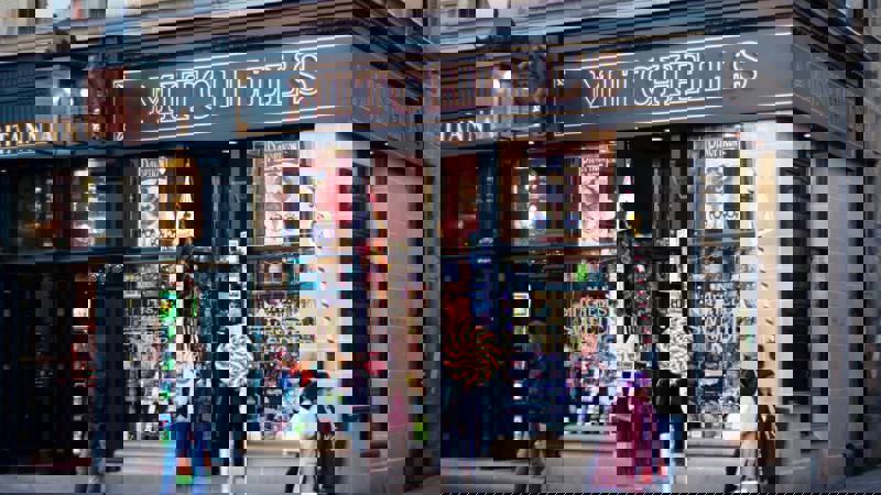 Exterior view of Mitchell's, a traditional-style sweet shop with a dark facade, large windows displaying colourful sweets, and a prominent "MITCHELL'S" sign.