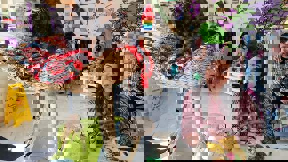 A person smiling at a cat cafe, with a cat perched on a cat tree and other patrons in the background.