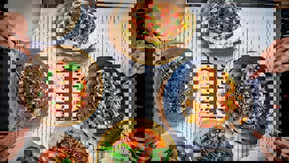 An overhead view of four people dining, with multiple plates of food on the table, including crab and scallops.