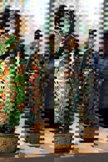 A close-up of several Chinese figurines, with the focus on a figure in a green robe.