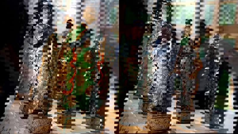 A close-up of several Chinese figurines, with the focus on a figure in a green robe.