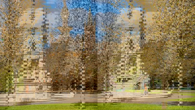 The Stewart Memorial Fountain in Kelvingrove Park with the Glasgow University main building's spire visible in the background.