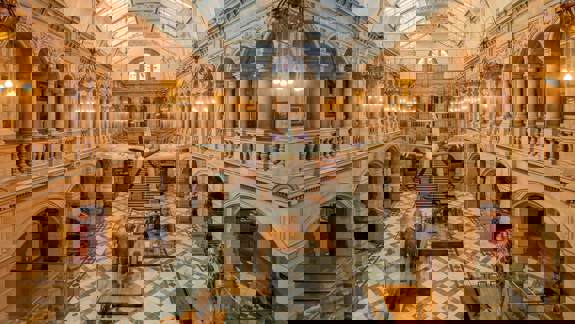 The grand, vaulted interior of a museum with a plane suspended from the ceiling and taxidermy animals, including an elephant and a giraffe, on the floor.