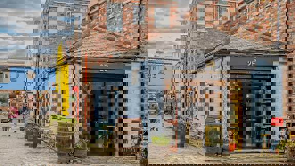 A cobbled alleyway with colourful buildings, including a small blue shop with a sign that reads "25."