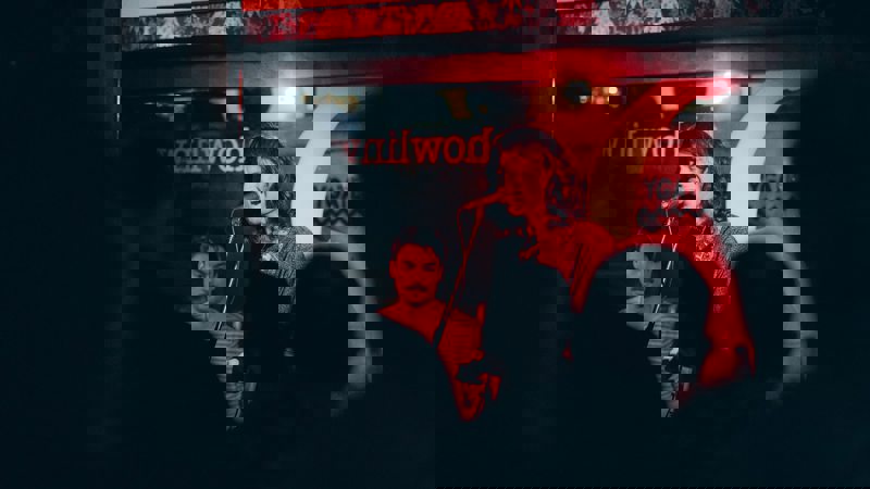 Singer performing under red lighting at The Howlin’ Wolf music bar, watched by an intimate audience.