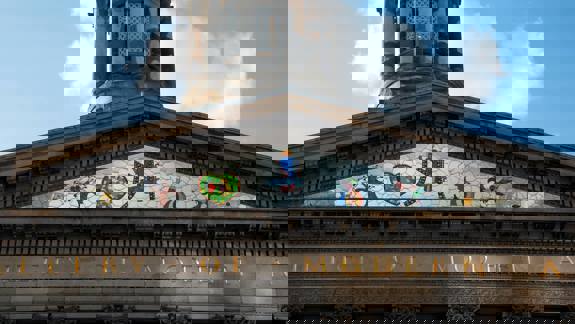 A colourful stained-glass mosaic depicting abstract figures in the tympanum of a building labelled "GALLERY OF MODERN ART."