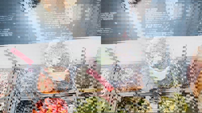 A bright, modern cafe interior with potted plants, hanging light fixtures, and a glass counter displaying food items.