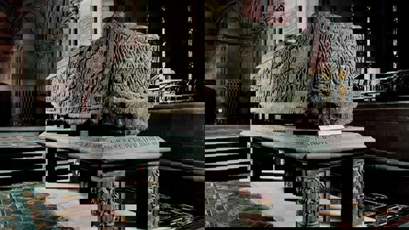 An ancient carved stone sarcophagus, known as one of the Govan Stones, is on display inside a historic church.