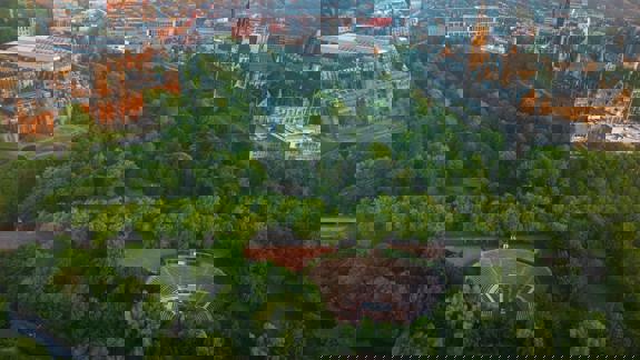 Aerial view of Glasgow city and Kelvingrove Park at golden hour, showing tree canopy, Kelvingrove Art Gallery and Museum, and University of Glasgow.