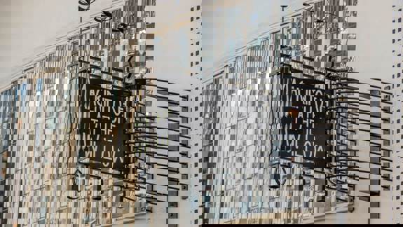 Exterior sign for "MACKINTOSH AT THE WILLOW" against a building with stained glass windows.