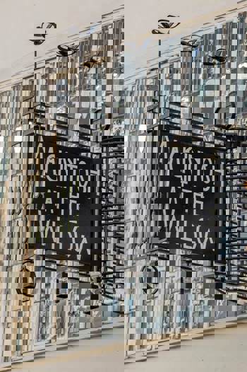 Exterior sign for "MACKINTOSH AT THE WILLOW" against a building with stained glass windows.