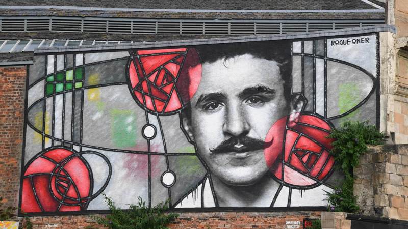 Mural of Charles Rennie Mackintosh in a stained-glass style with red roses on a building.