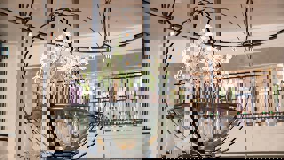 Close-up of a large metal chandelier hanging from the ceiling, with glass elements holding white flowers.