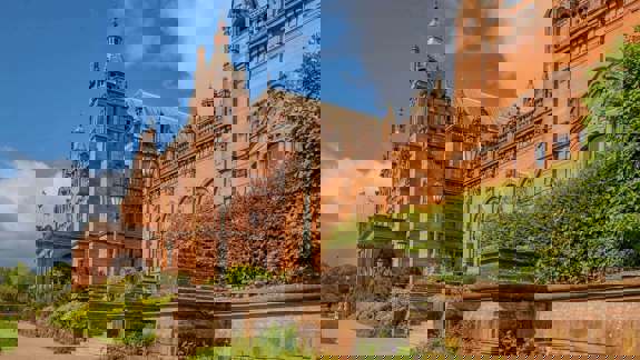 Exterior view of the ornate, red sandstone Kelvingrove Art Gallery and Museum under a blue sky.