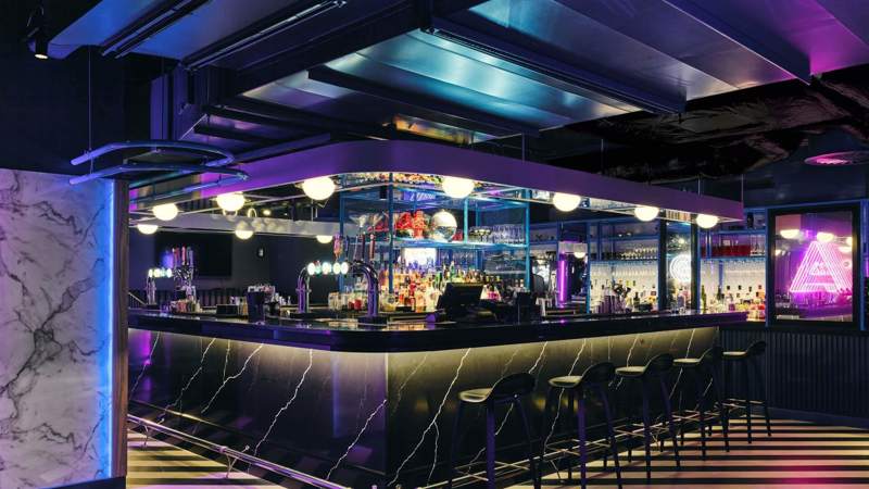 Black marble bar with neon lights and striped floor.