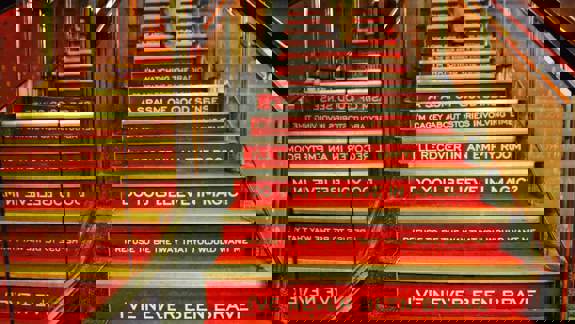 An interior view of red stairs, each riser painted with white song lyrics from the band Biffy Clyro, including "I'll recover in an empty room."