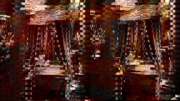 Luxurious room at House of Gods Glasgow with dark wood panelling, tiger-print canopy bed, and rich velvet drapes creating a glamorous, opulent atmosphere.