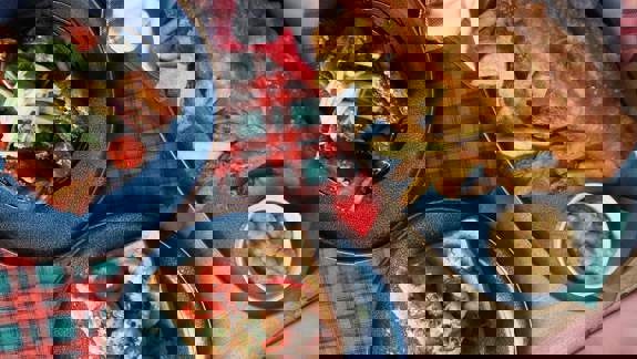 A rustic meal featuring a large plate of classic fish and chips with mushy peas, and two plates of salad and prawns on toast.